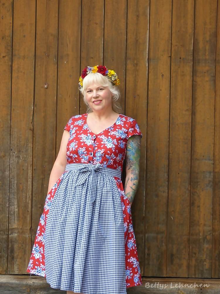 dirndlkleid sissi gr. 32 50 Frau in Blumenkranz und geblümtem Kleid vor Holzwand