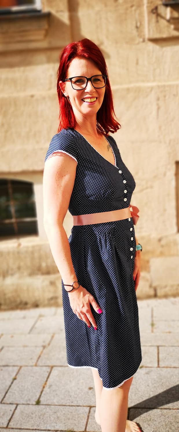 dirndlkleid sissi gr. 32 50 Frau im gepunkteten Kleid lächelt im Sonnenschein.