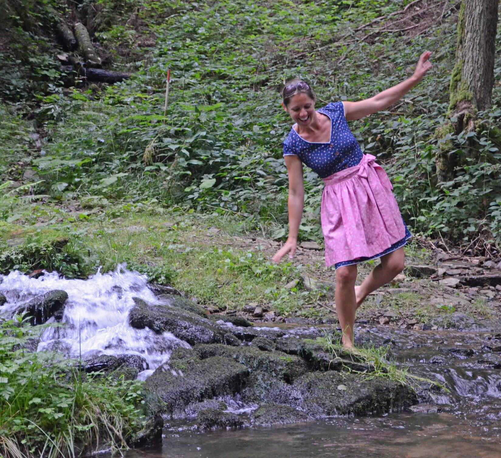 dirndlkleid sissi gr. 32 50 Frau balanciert auf Steinen neben Bach im Wald.