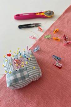 Nähzubehör auf korallenfarbenem Stoff mit Rollschneider