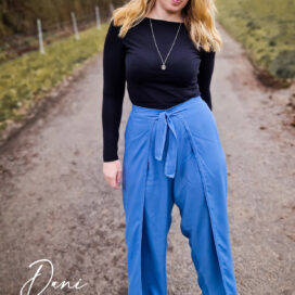 Frau auf Landstraße mit blauer Hose und schwarzem Oberteil.