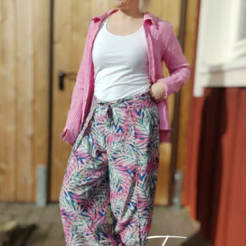 Frau in Sommerkleidung, pinke Jacke, Hut, Sonnenbrille.