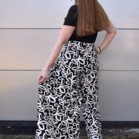 Person in gemusterter Hose und Sonnenbrille von hinten.