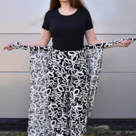 Frau im schwarz-weiß gemusterten Outfit, lächelnd, Sonnenbrille