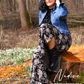 Frau im Wald auf Baumstumpf sitzend