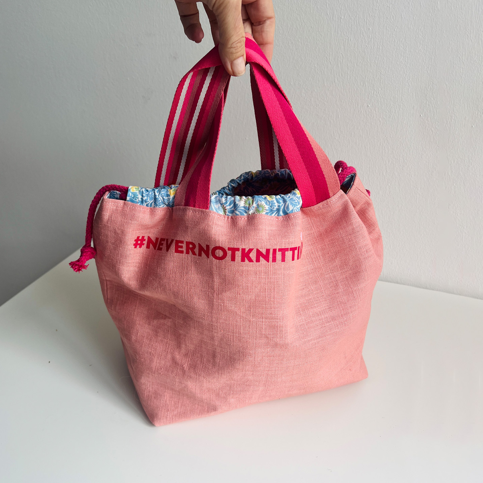 Rosa Tasche mit bunten Griffen und Aufdruck