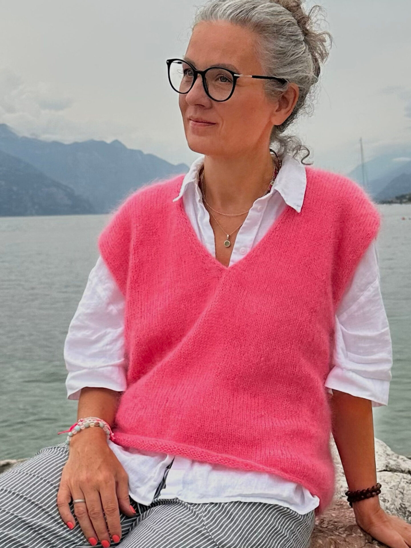 Frau in rosa Pullover am Wasser.