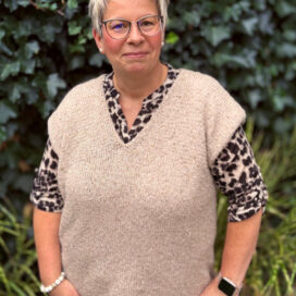 Frau mit modischer Kleidung vor grüner Wand.
