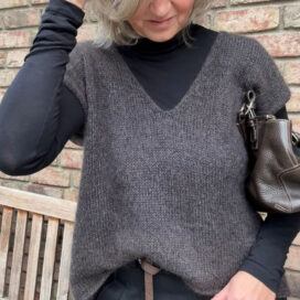 Frau in grauem Oberteil vor Ziegelwand