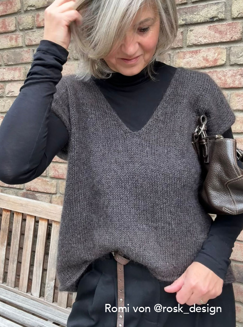 strickanleitung sweatervest lisbeth Frau in grauem Oberteil vor Ziegelwand
